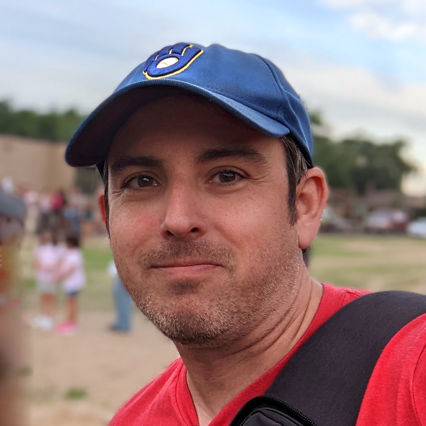 A closeup head shot of Ryan Marx. He's smiling softly and wearing a Milwaukee Brewers ballcap.
